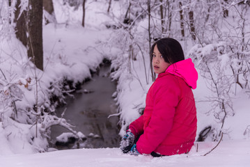 Young Asian girl sitting in snow