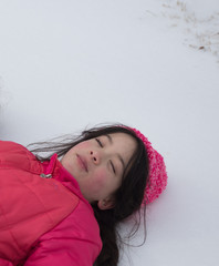 Young Asian girl laying in the snow