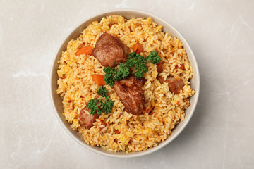 Obraz na płótnie Canvas Bowl with delicious rice pilaf on light background, top view