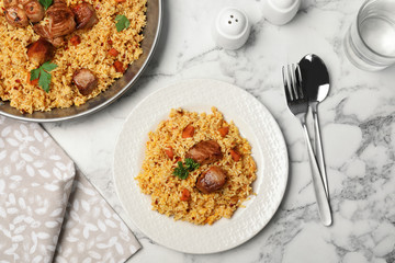 Tasty rice pilaf with meat served on marble table, flat lay