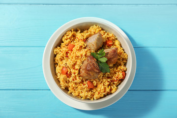 Bowl with delicious rice pilaf on wooden background, top view