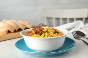 Bowl of tasty rice pilaf with meat served on table