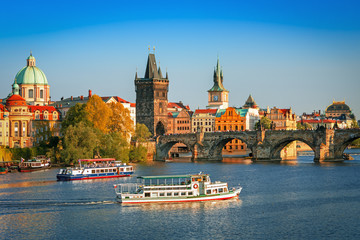 Fototapeta premium Malowniczy widok na rzekę Wełtawę, most Karola i historyczne centrum Pragi, budynki i zabytki starego miasta o zachodzie słońca, Praga, Czechy