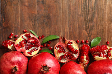 Flat lay composition with ripe pomegranates and space for text on wooden background