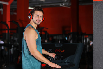 Fototapeta na wymiar Young man listening to music with headphones at gym