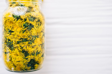 Dandelions in a glass jar on a white background