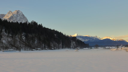  	Mornig panorama on village in valley covered with mist. Garmisch-Partenkirchen