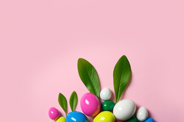 Creative flat lay composition with Easter bunny ears made of green leaves and eggs on color background, space for text