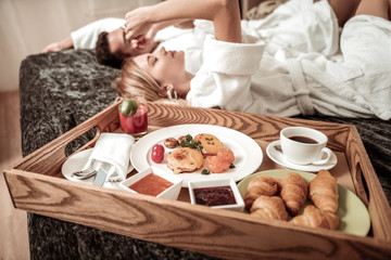 Obraz na płótnie Canvas Close up of yummy breakfast standing on bed near couple