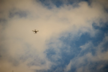 Far away of flying drone on cloudy blue sky and maybe it will out of control. Professional camera drone flying in blue sky and fully clouded. Abstract idea of espionage.
