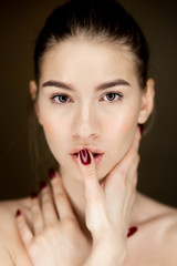 Portrait of young charming girl with natural makeup holding her hands on her face