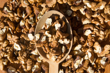 Closeup of Peeled Walnuts pile. Walnuts Background. Walnuts on wooden cutting board with wooden spoon. Selective focus