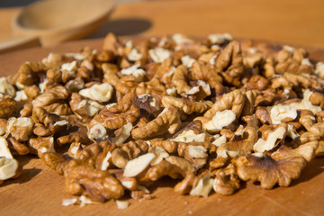 Closeup of Peeled Walnuts pile. Walnuts Background. Walnuts on wooden cutting board with wooden spoon. Selective focus