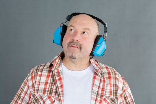 man with shaved head in bluetooth headphones