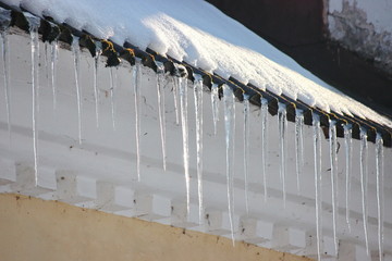 Water drops on the roof. icicles melt under influence of warm air and sun. Spring influence in the world. Modifying the pores of the years. The sun's rays change aggregate state of ice to water