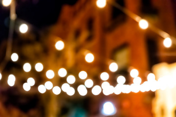 Bokeh abstract background with yellow and orange circles illuminated decoration lights at night evening dark street blurry blurred restaurant building in urban city