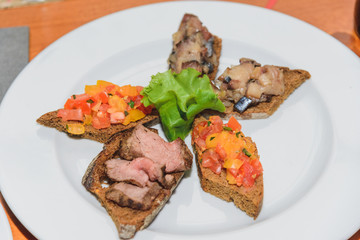 Five small sandwiches with different fillings are on a white plate.