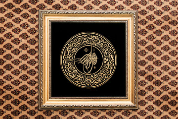Tughra Ottoman Turkish muslim signature. Luxury arabic ligature embroidered with golden silk threads on black velvet background, seal or signature. Bismillah tugra Islamic framed calligraphy