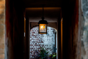 Nobody in old vintage stone brick architecture and narrow dark alley with illuminated silhouette lantern passage tunnel