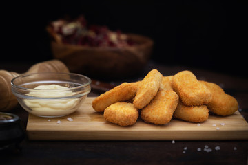 Chicken nuggets and sauce on dark wooden background. Front view