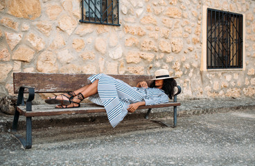 Woman laying down on a chair near a stone house in a village