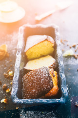 Yogurt plumcake made with almond and gluten free, with colored easter egg, shot from a top viewpoint over a rusty wooden black background,flare added