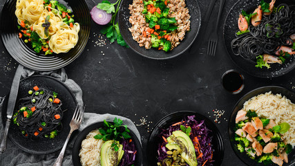 A set of food and dishes. Pasta, rice, risotto, salad. On a black background. Free copy space.