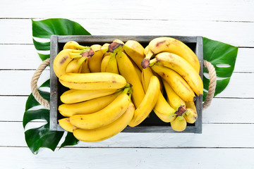 Fresh bananas in a wooden box. Top view. Free copy space. © Yaruniv-Studio