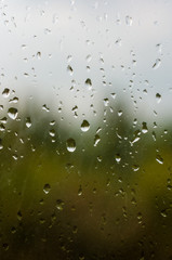 raindrops on window glass on background of cloudy sky