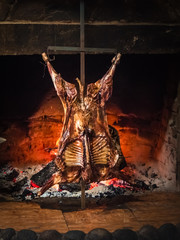 Lamb of Patagonia slowly roasted over the fire, typical dish of Chile and Argentina. Lamb to the post - obrazy, fototapety, plakaty