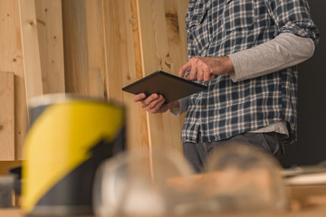 Carpenter using digital tablet in small business woodwork workshop