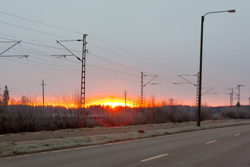 Beautiful sunrise at road and railroad at autumn in Finland.