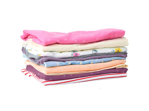 Stack of colorful cute girl clothes. A pile or heap of freshly washed and ironed colorful cute girl clothes isolated on white background. Children fashion.