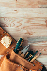 Carpentry tool belt on woodwork workshop desk, top view