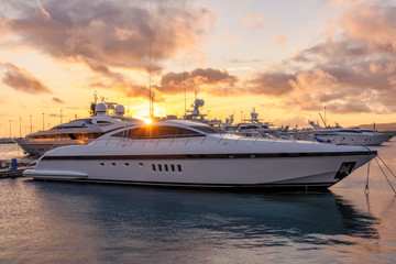 Beautiful orange sunset in the sea harbor with moored yachts. Expensive 92 foot yacht at the pier...