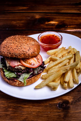 Hamburger close-up on black background. Fresh vegetables and grilled meat.