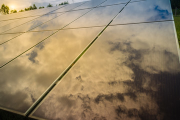 Solar cells (photovoltaic panel) with the reflection of sunlight, blue sky and white clouds. Solar energy is radiant light and heat from the Sun such as solar heating and photovoltaics power plant.