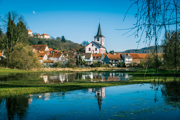 Fototapeta na wymiar Michaelskirche, Schloss Reichenberg und das Dorf Reichelsheim spiegeln sich im Winterweiher der Stockwiese