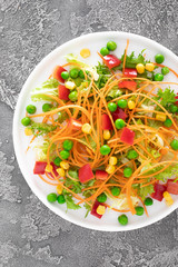 Fresh vegetable salad with raw carrot, green peas, corn, sweet pepper and lettuce. Healthy vegan, vegetarian lunch menu. Top view