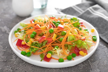 Fresh vegetable salad with raw carrot, green peas, corn, sweet pepper and lettuce. Healthy vegan, vegetarian lunch menu. Top view