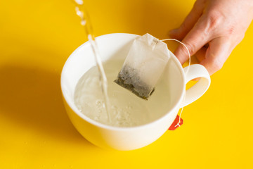 man makes a tea bag in a white cup