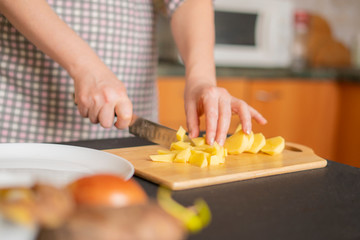 Obraz na płótnie Canvas housekeeper cuts potatoes on a wooden board