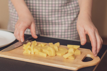 housekeeper cuts potatoes on a wooden board