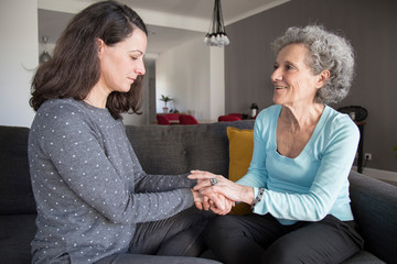 Elderly woman and her daughter chatting and holding hands