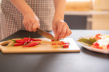 Obraz na płótnie Canvas woman in the kitchen cutting chili