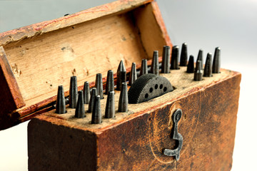 Fototapeta na wymiar A vintage circular round corner punches set with an anvil with apertures in a wooden box. On a gray background.