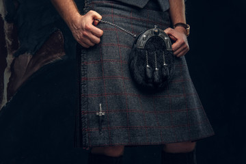 Traditional Scottish costume. Kilt and sporran. Studio photo against a dark textured wall