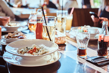 Young friends dine in the cafe outdoors. Close-up image of a table with different dishes and drinks