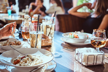 Young friends dine in the cafe outdoors. Close-up image of a table with different dishes and drinks