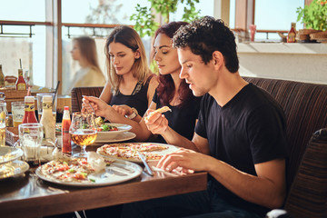 Young friends enjoying pizza and salad in a outdoor cafe